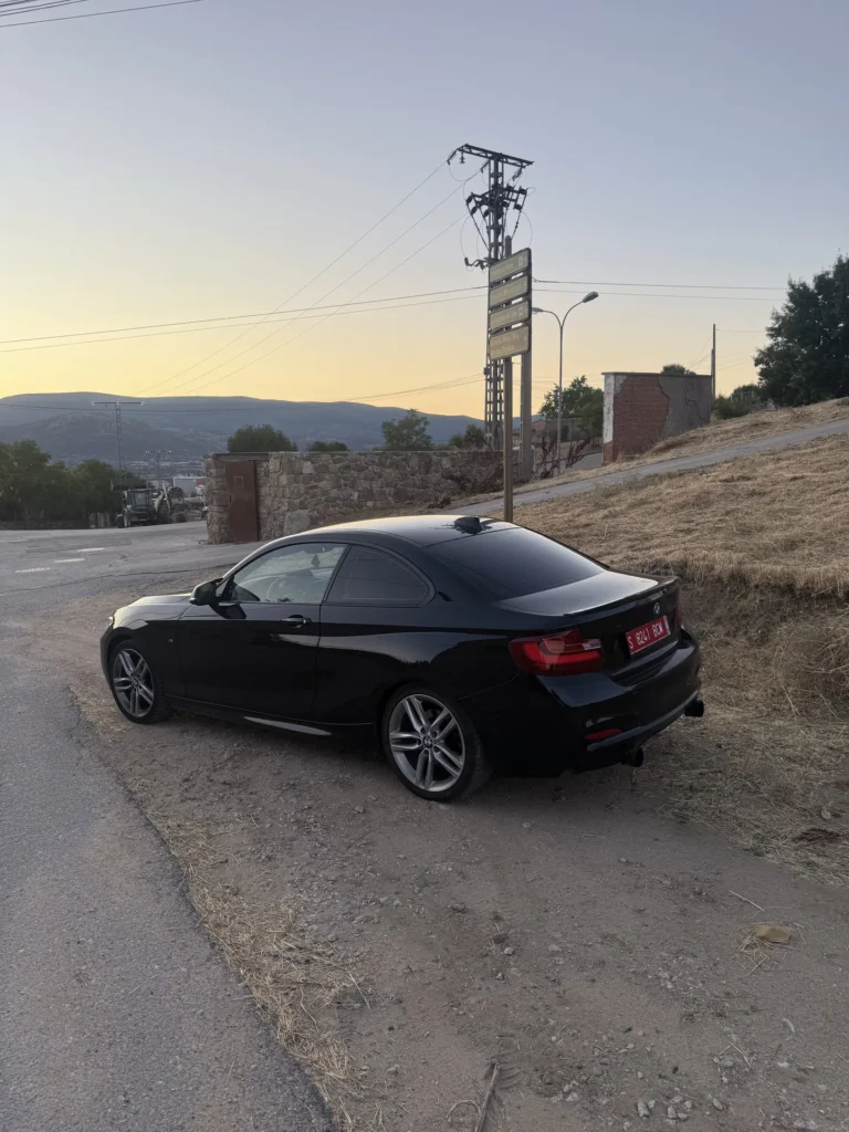 Lateral de un BMW Serie 2 M Sport negro en una carretera al atardecer