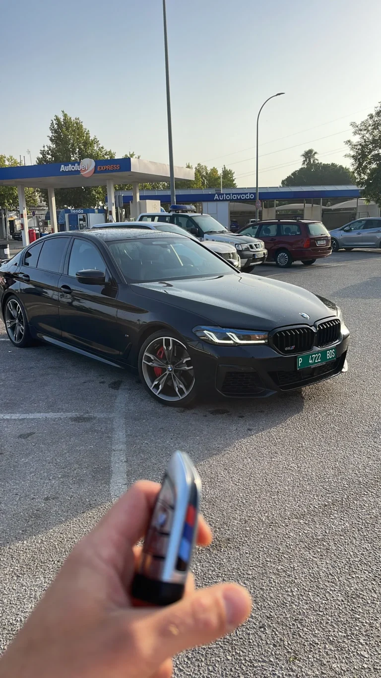 Mano sosteniendo la llave de un BMW Serie 5 M Sport negro con matrícula de exportación